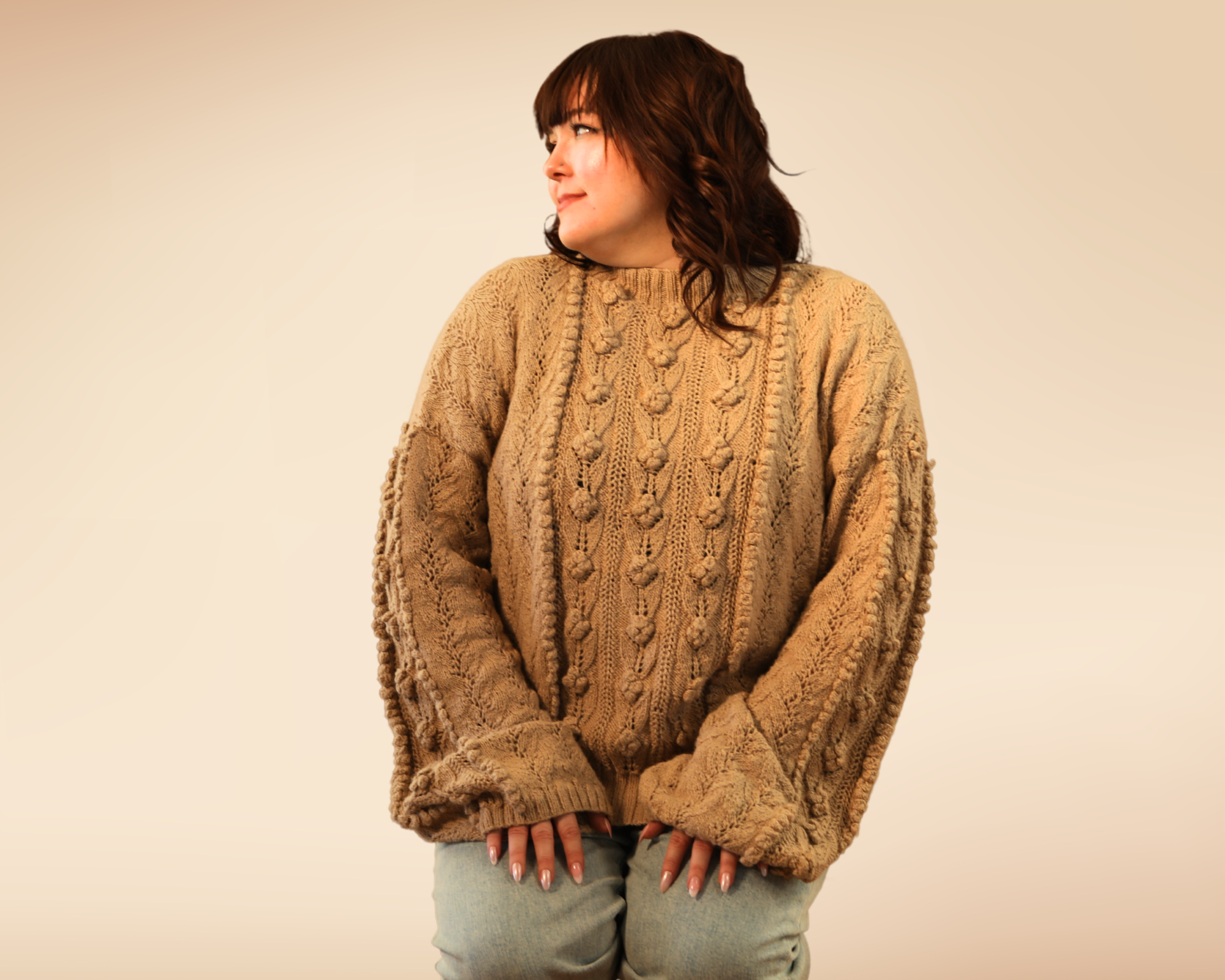 Gigi kneeling with the rose sweater showing the arm details